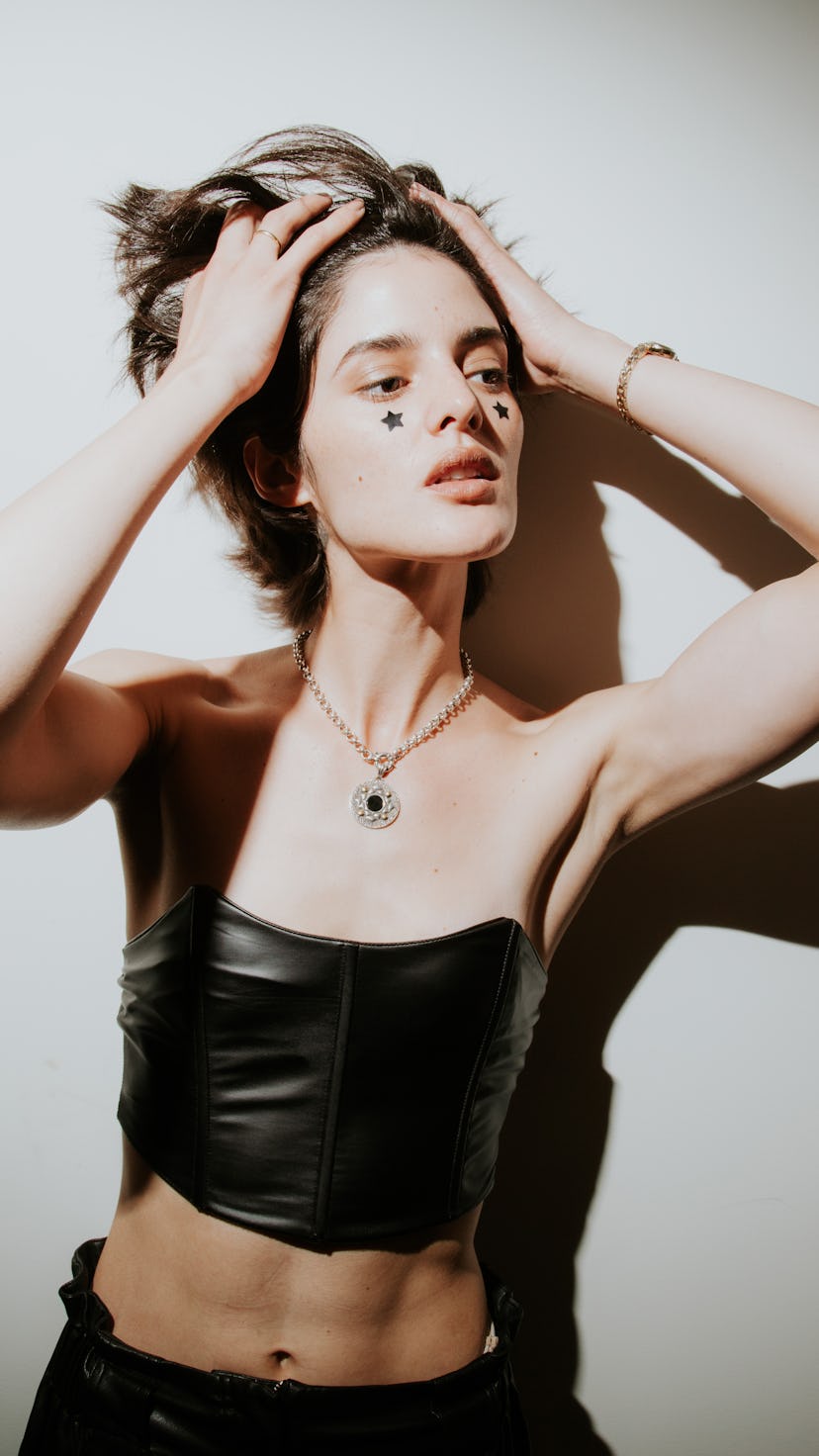 A model with stick on stars under her eyes in a black outfit and flashy necklace