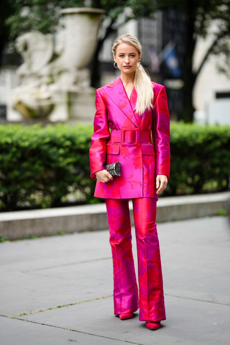 Victoria Magrath wearing gold earrings, a red and neon pink print pattern blazer jacket and matchin...