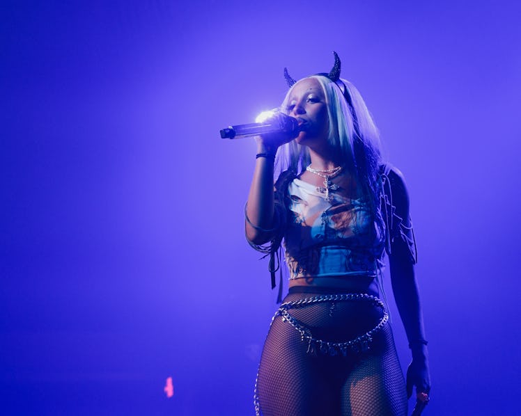 Doja Cat holding a microphone while performing 