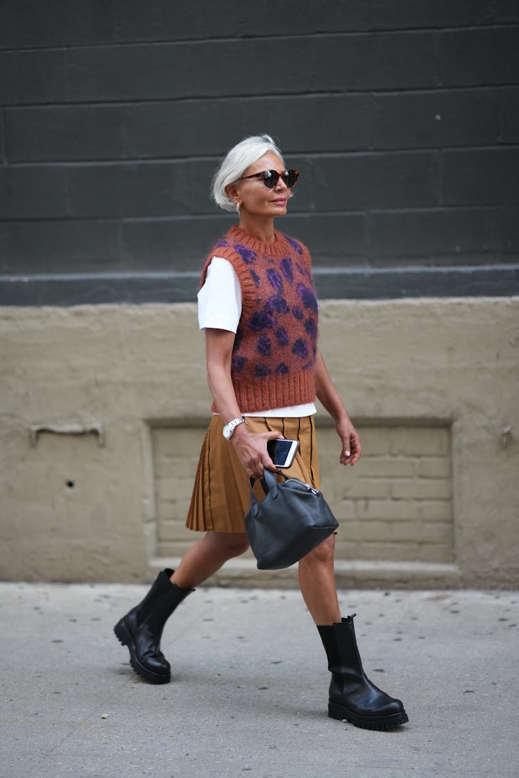 Grece Ganhem wearing sunglasses, a white t-shirt, a brown pullover, pleated skirt, black bag boots, ...