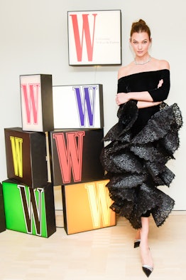 the model Karlie Kloss posing in front of a display of the W logo