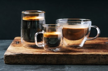 Coffee and espresso in three glass cups on a wooden serving board
