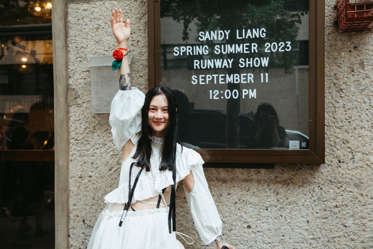 Japanese Breakfast’s Michelle Zauner standing in front of an announcement board for Sandy Liang's NY...