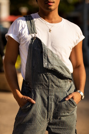 A man in a white shirt and grey overalls close-up