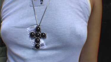 A closeup of a person wearing a white tank and black crucifix