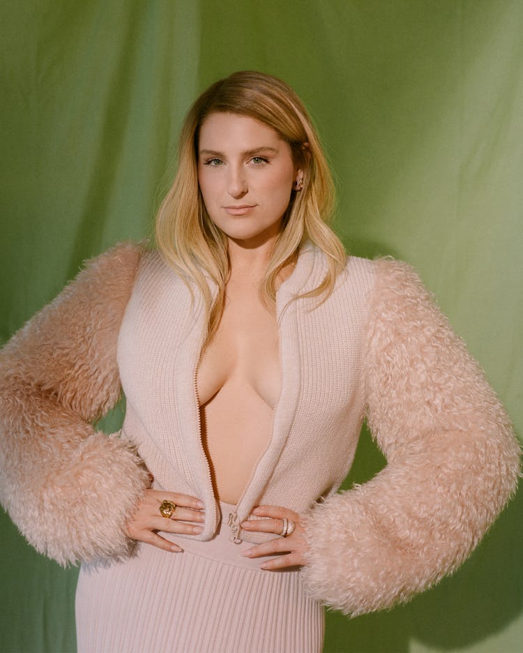 Meghan Trainor poses in front of green curtains in an unzipped pink Fendi jacket.