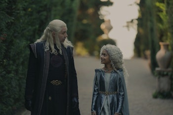 Viserys Targaryen and Laena Velaryon walking through a garden from the tv show The House Of The Drag...