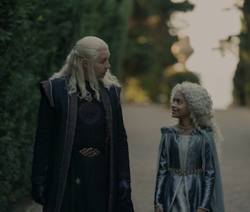 Viserys Targaryen and Laena Velaryon walking through a garden from the tv show The House Of The Drag...