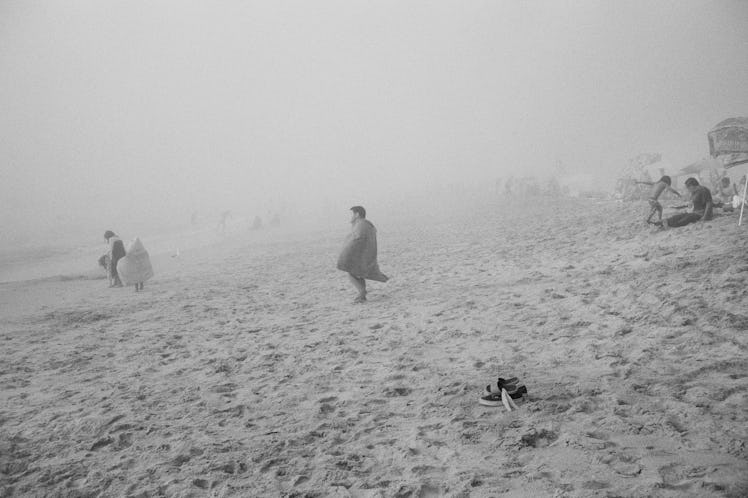 A boy standing on a very foggy beach