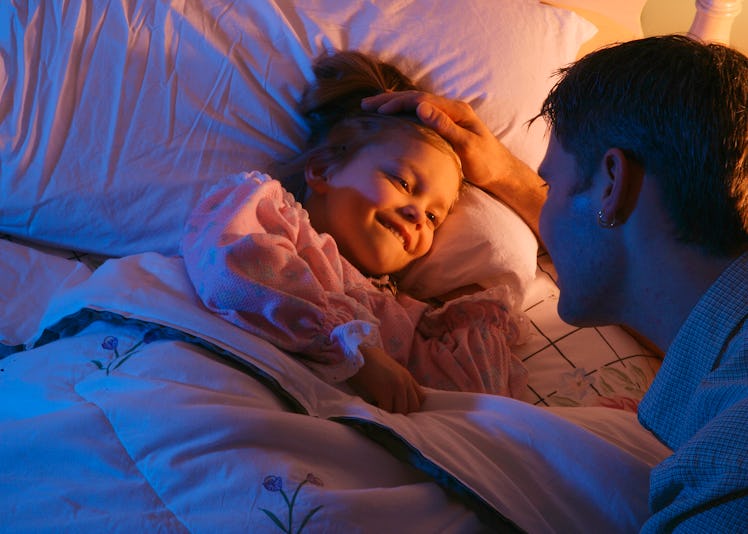 A dad tucks in his daughter for bed.