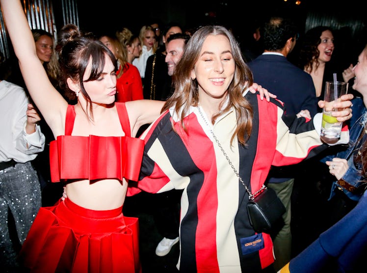 Two women at a W party, dancing and holding their drinks 