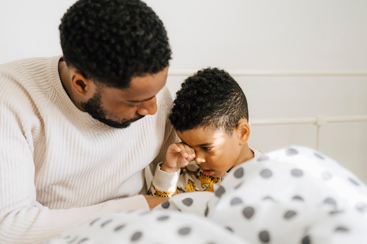 A dad sits in bed with his tired son before bedtime.