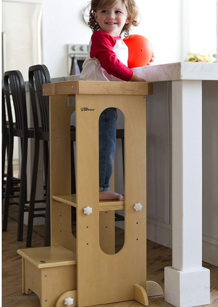 Toddler standing in natural wood learning tower