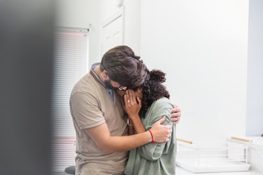 A man comforts his wife after a miscarriage by hugging her while she cries.