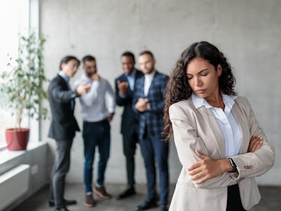 A group of men jeer at a woman; sexual harassment at work