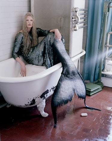 Kristen McMenamy sitting in a tub wearing a mermaid outfit