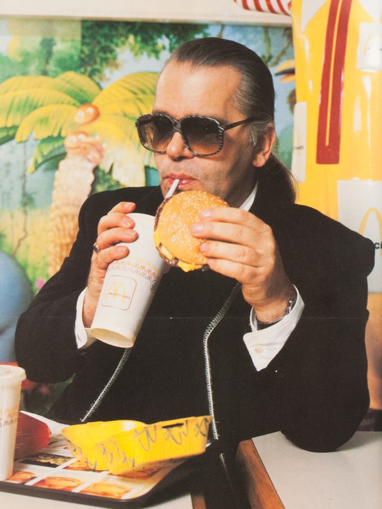 Karl Lagerfeld eating a McDonald's burger and drinking coke from a white cup with a straw