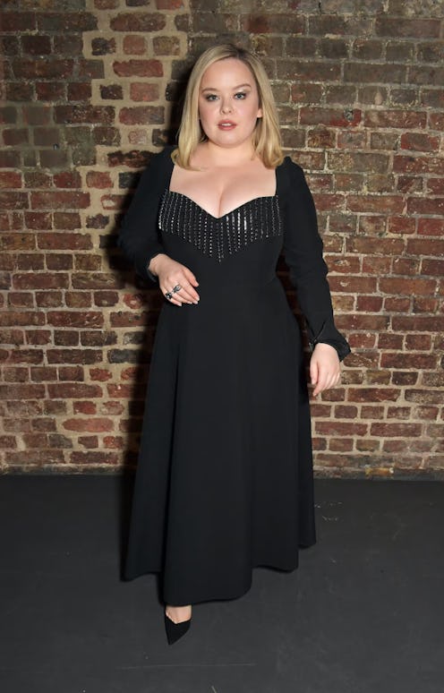 Nicola Coughlan posing in a black dress and black heels