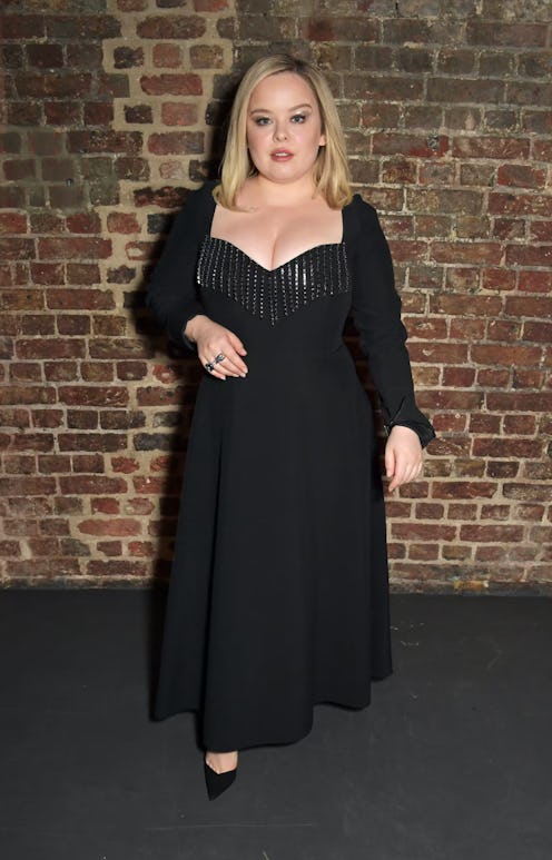 Nicola Coughlan posing in a black dress and black heels