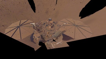 color photo of a robotic lander with dust covered solar panels on a dusty brown landscape