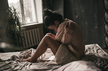 A woman cries alone on a bed after a miscarriage.