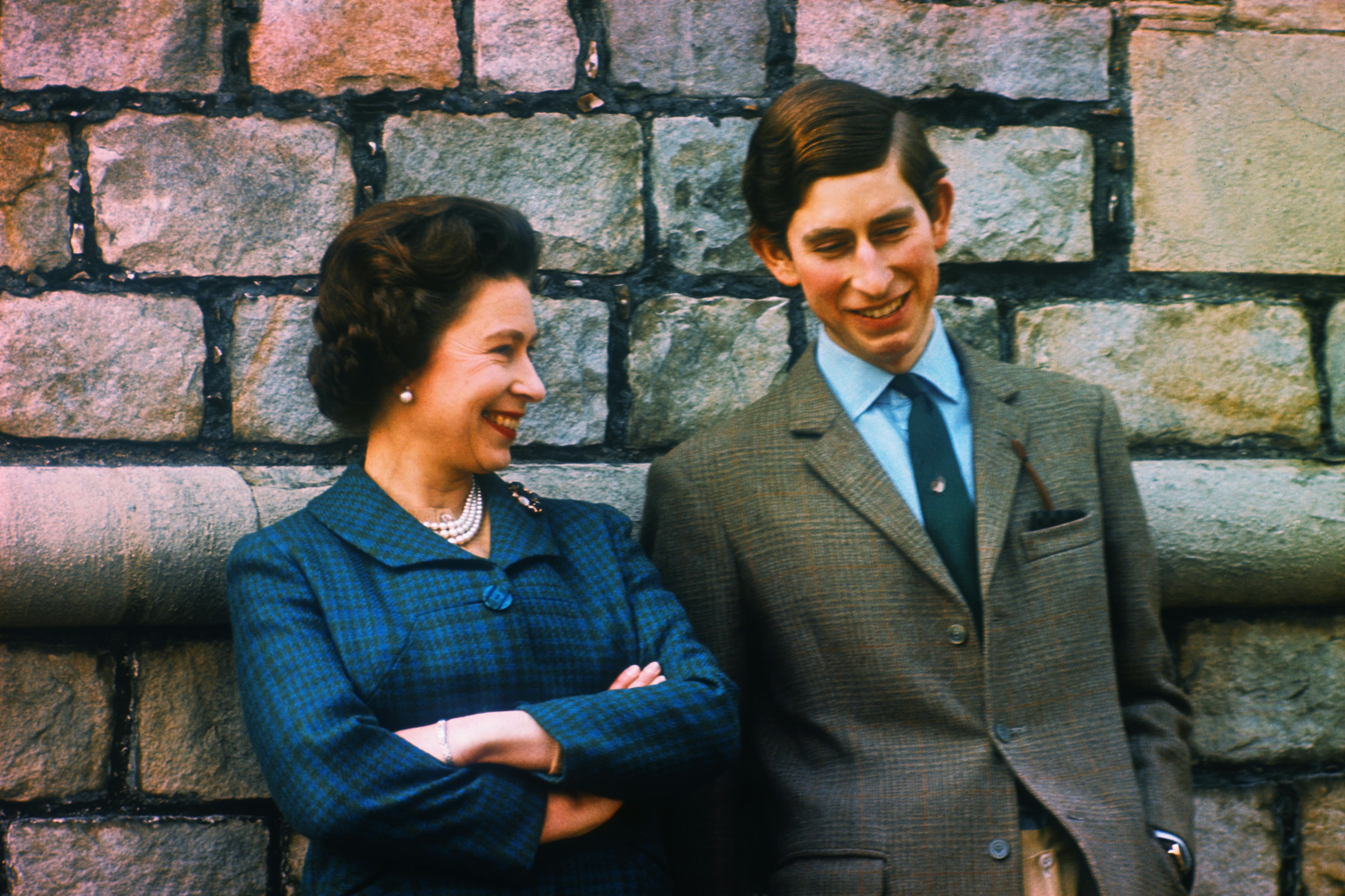 Young Queen Elizabeth and Prince Charles stand by a wall at their Windsor home.