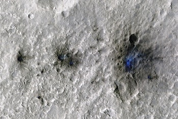 color photo of a line of three craters on a gray rocky surface