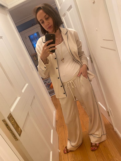 Emily Holland taking a mirror selfie in a matching satin set of a shirt and pants and a white top
