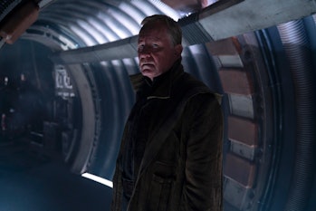Luthen Rael (Stellan Skarsgard) stands in a dimly lit, futuristic hallway.