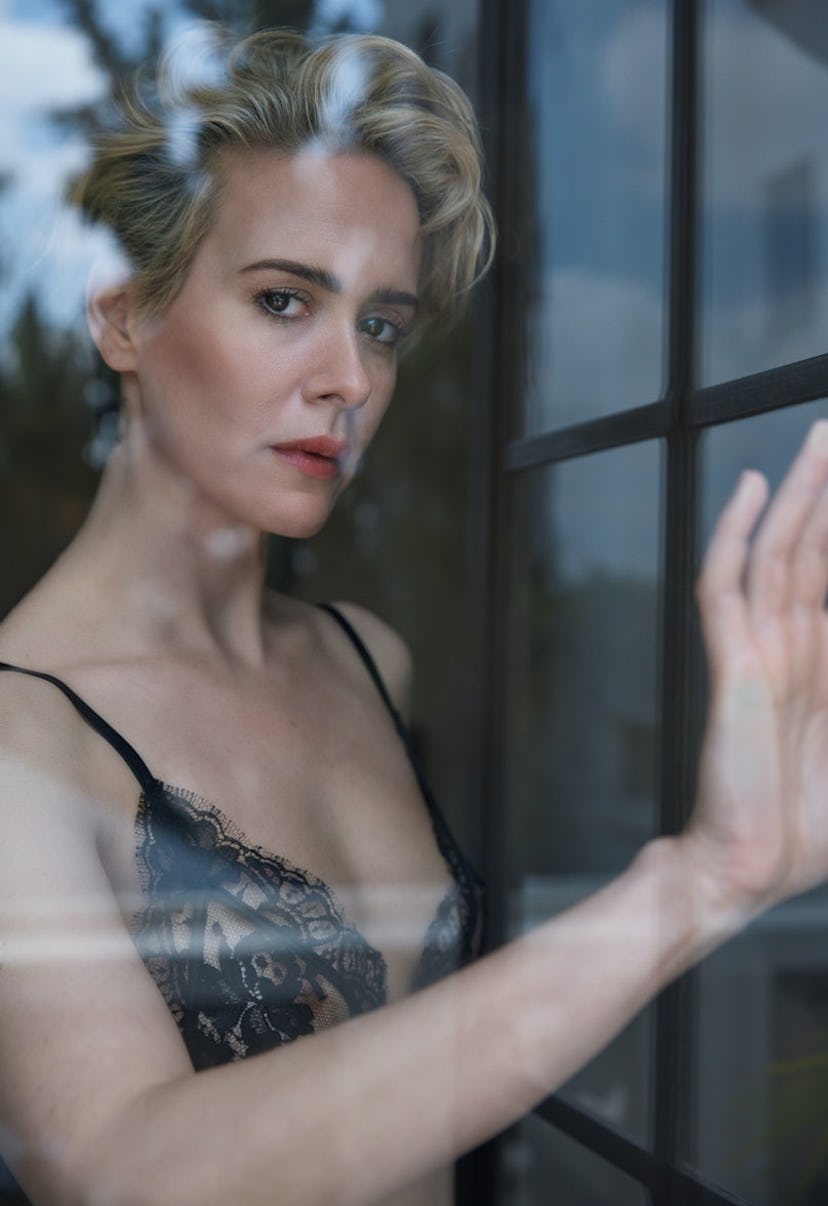 Sarah Paulson wearing a bra and posing behind a window