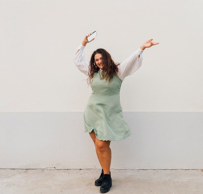 Young woman waving her arms in the air after reading the spiritual meaning of the September 2022 new...