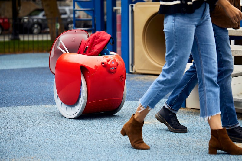 A gita robot carries people's bags on a playground.