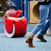 A gita robot carries people's bags on a playground.