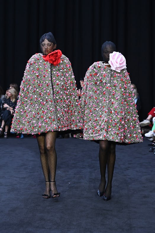 Two models in rose embroidered coats with extensive flower detail tributing Queen Elizabeth II, desi...