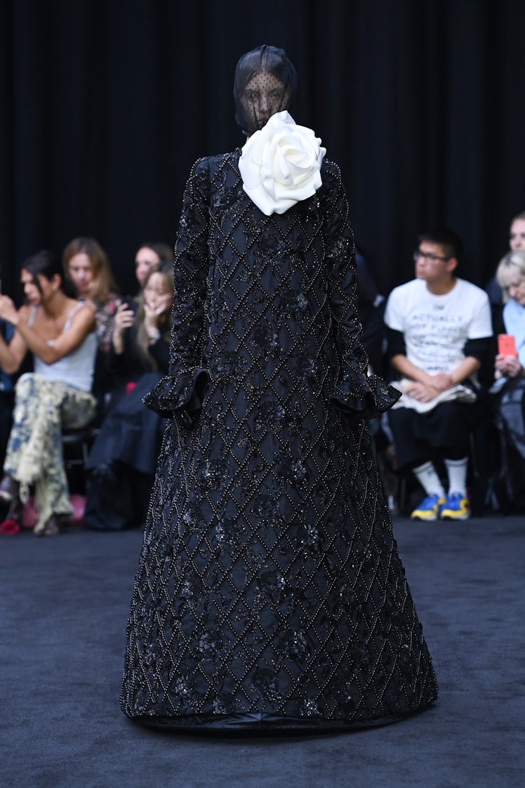 A model standing in a black gown with a face veil at the Richard Quinn spring 2023 runway 