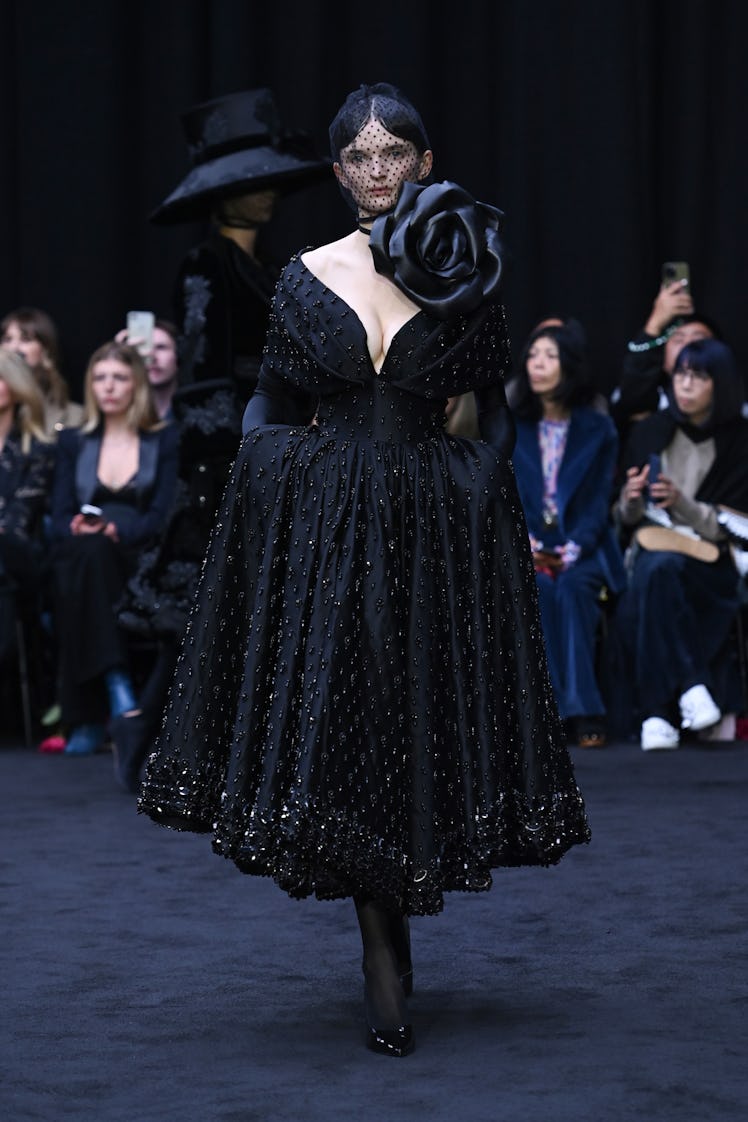 A model walking in a black dress at the Richard Quinn spring 2023 runway