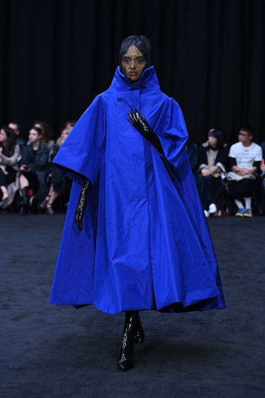 Blue cape-dress accessorized with the black gloves, boots and veil as Richard Quinn’s tribute to Que...