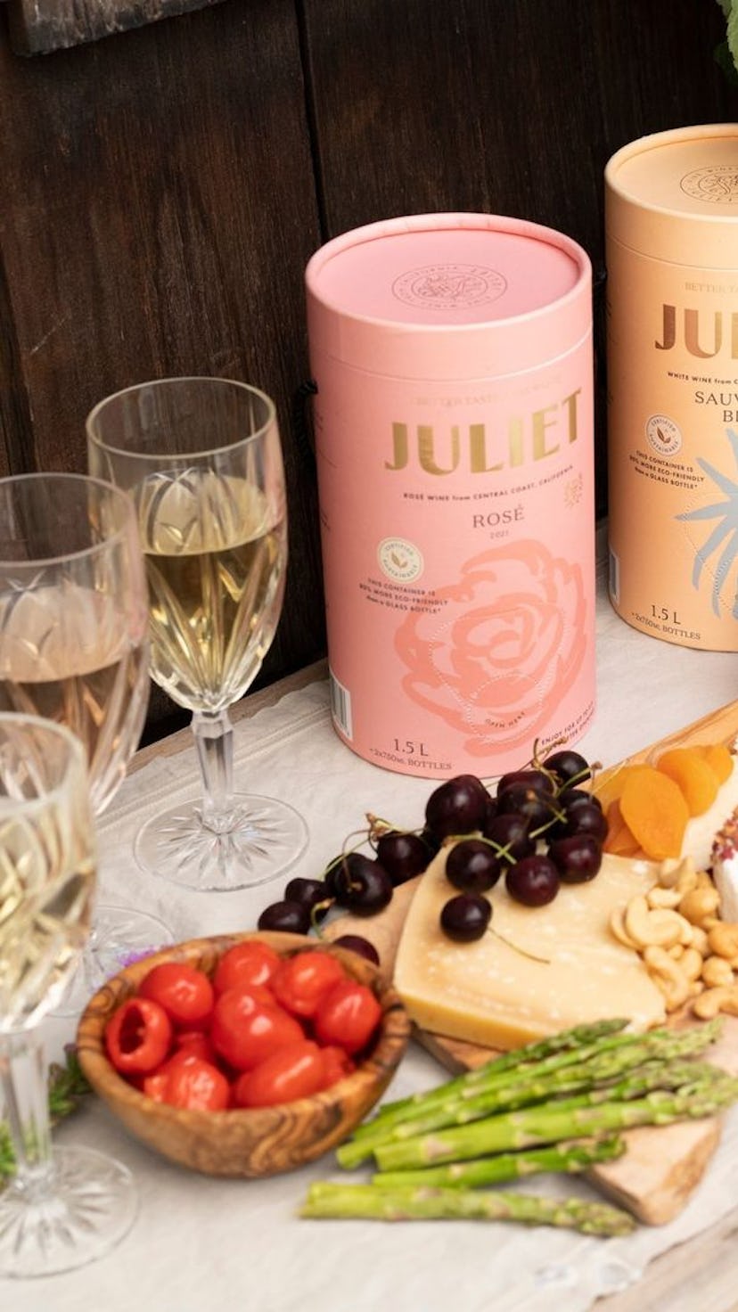 Two boxed wine packs of Sauvignon Blanc and Rose by Juliet next to glasses and a charcuterie board