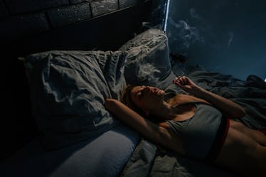 A woman smoking weed in bed.