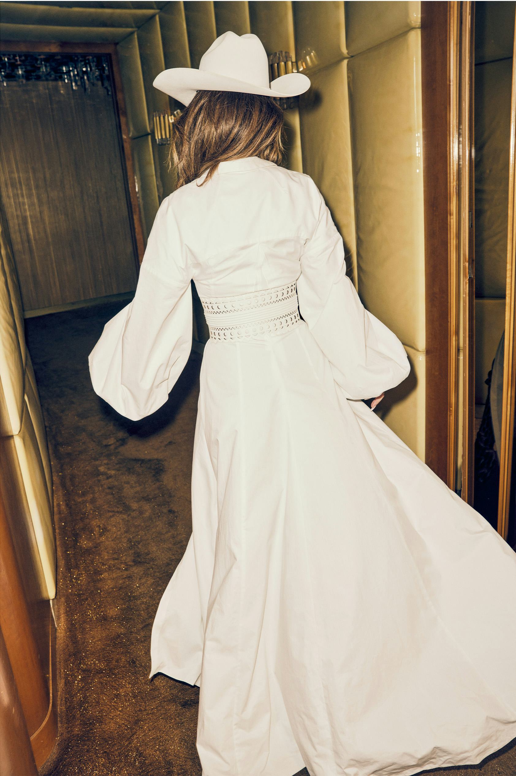 Shania Twain walking in a white Carolina Herrera dress and Stetson hat