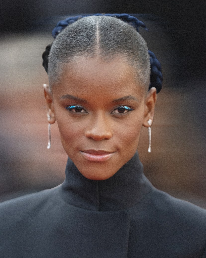 A photo of Letitia Wright with her hair parted in the middle in a slicked back style with a navy bow