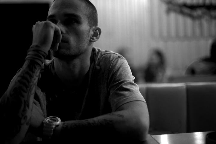 Man sitting at a bar alone, looking unhappy.