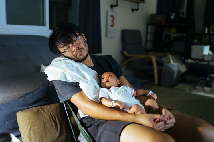 A dad sleeping in a chair with baby in his lap.