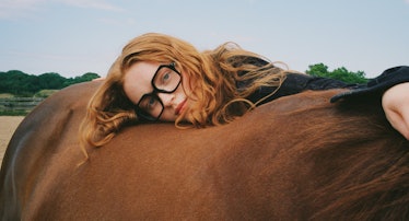 Sadie Sink wearing glasses and leaning her head on a horse's back in a Stella McCartney campaign