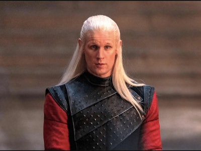 Matt Smith as Daemon Targaryen standing in traditional garb and with long blond hair.