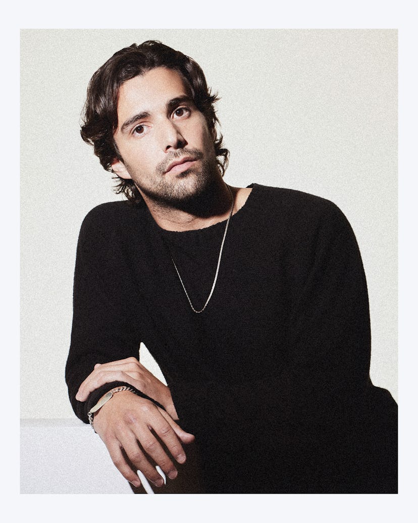 Fabien Frankel from House of the Dragon posing in a black shirt with a thin necklace