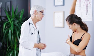 A woman examines her breast during a doctor's appointment.