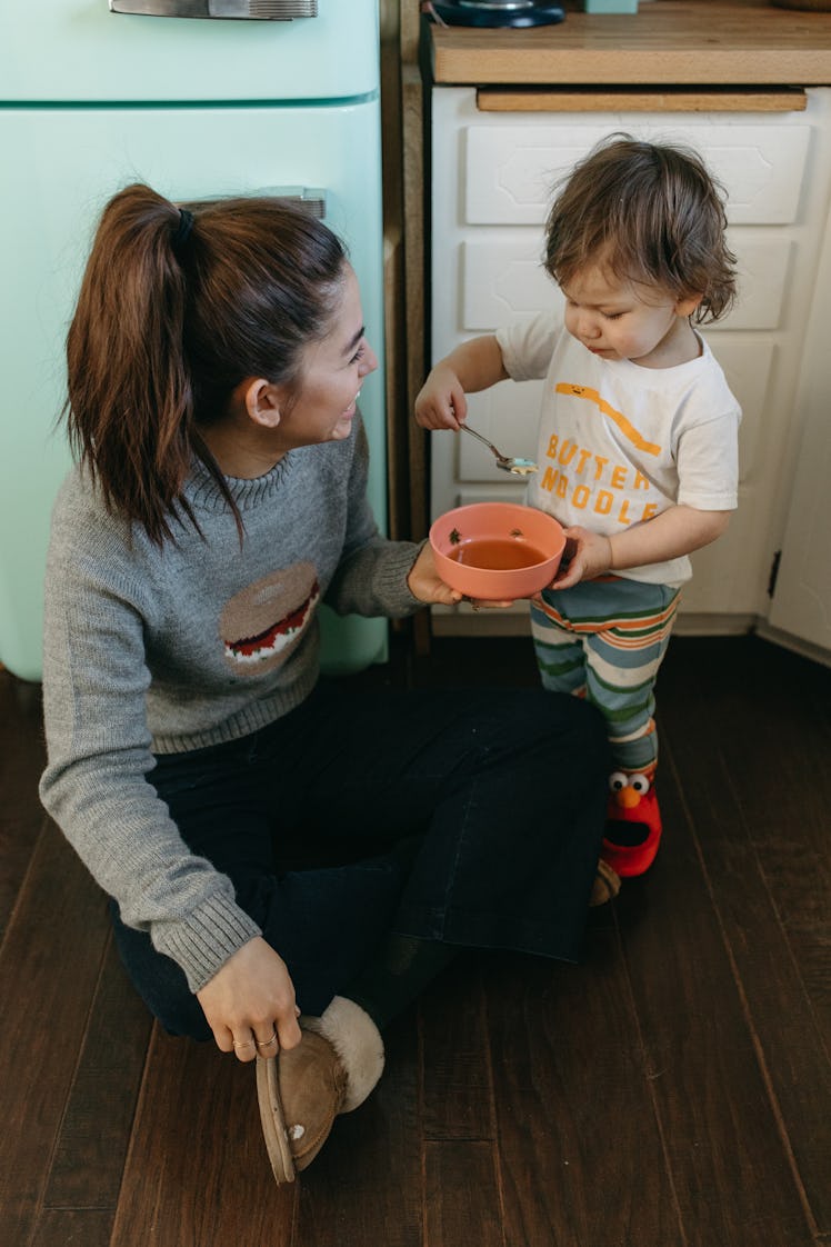 Molly Yeh and her daughter, who is eating a bowl of chicken and stars soup.