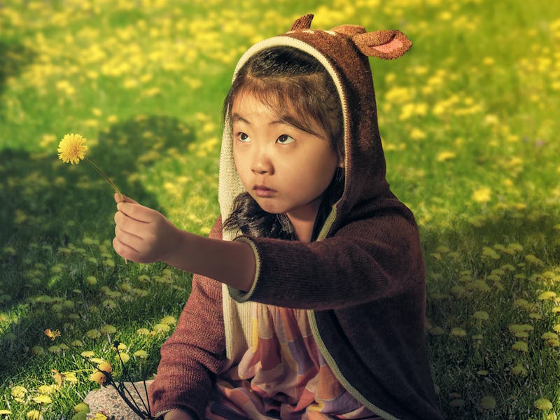 Wen (Kristen Cui) holds up a dandelion in the poster for M. Night Shyamalan's Knock at the Cabin
