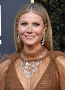 A smiling Gwyneth Paltrow wearing dangling diamond earrings